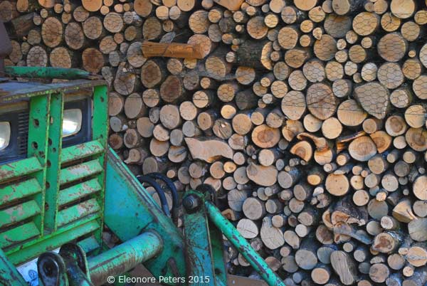 gestapeltes Holz und grüner Traktor