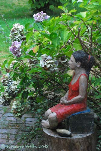 Plastik: sitziende Frau mit rotem Kleid